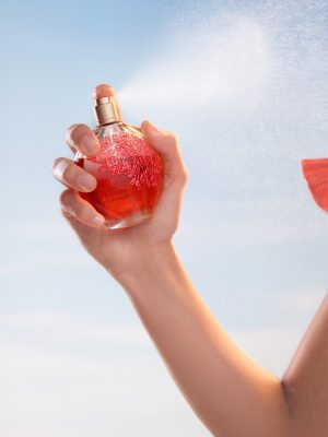 Mulher segurando um perfume de o boticário